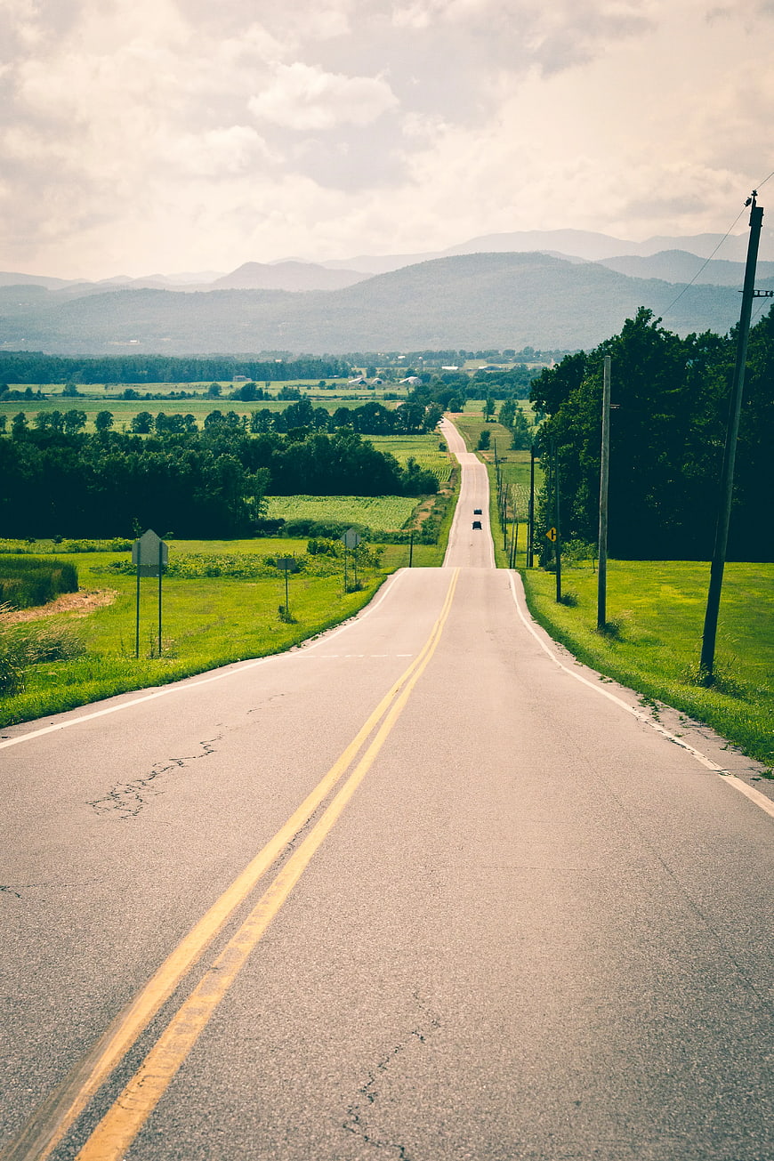 Winding Country Road Through Green Fields and Mountains