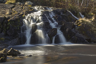 Serene waterfall cascading over mossy rocks in autumn forest