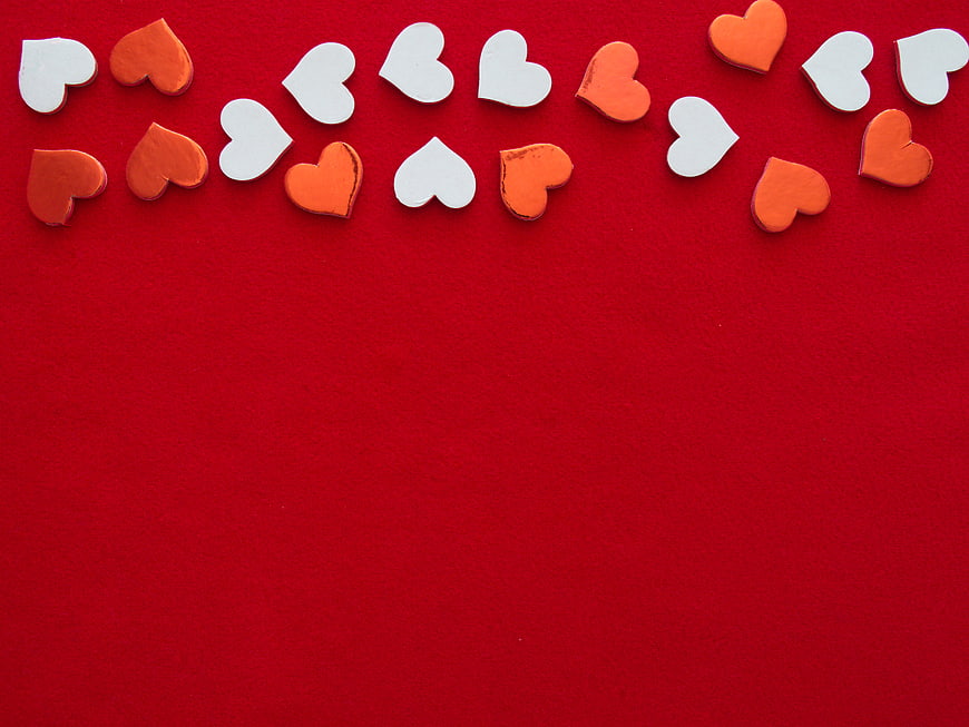 Red background with scattered white and orange paper hearts