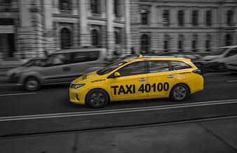 Yellow taxi driving on city street with motion blur