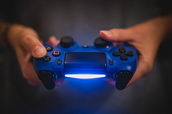Hands holding blue PlayStation 4 controller with glowing light