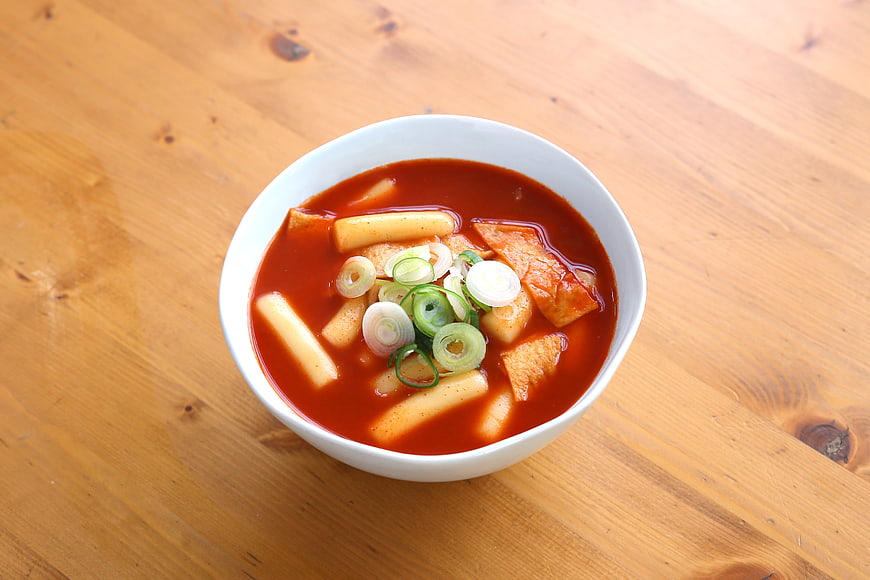 Bowl of spicy Korean tteokbokki with rice cakes and green onions