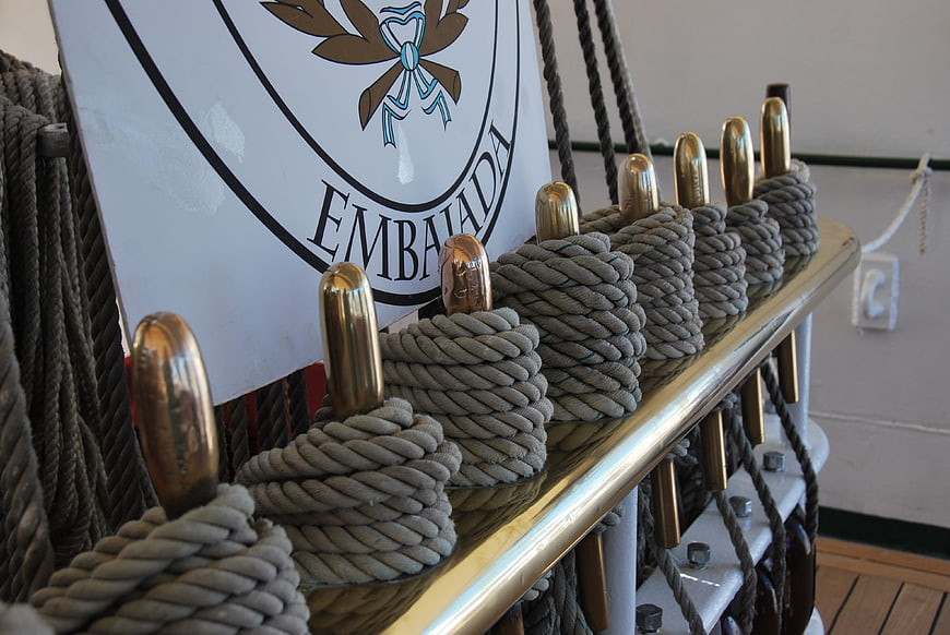 Close-up of ship cleats with coiled ropes and Embajada flag
