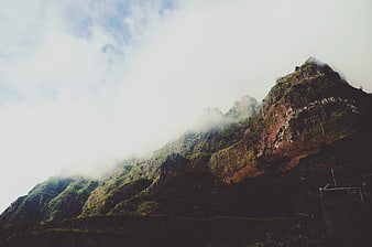 Misty Mountain Peak with Green Vegetation and Clouds