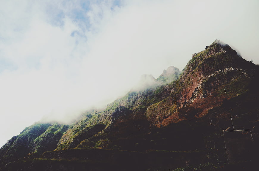 Misty Mountain Peak with Green Vegetation and Clouds