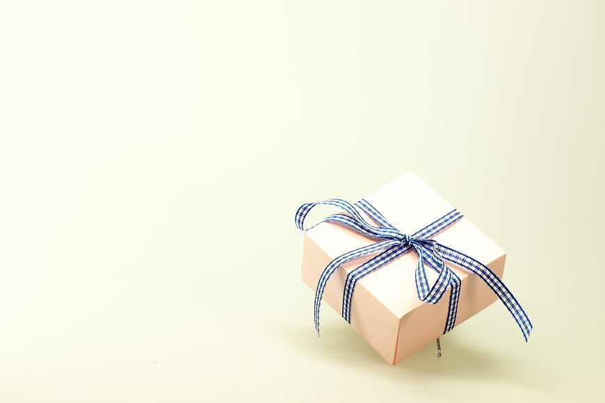 White Gift Box with Blue Ribbon on Cream Background