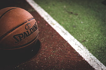 Spalding basketball resting on a red track next to a green field