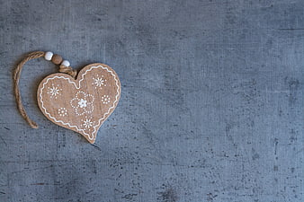 Rustic wooden heart ornament with white floral details on gray textured background