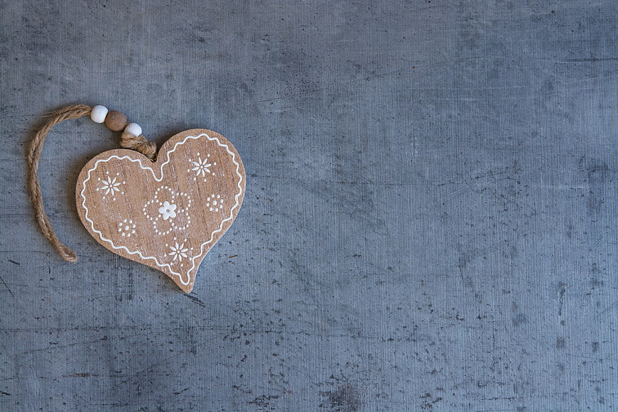Rustic wooden heart ornament with white floral details on gray textured background