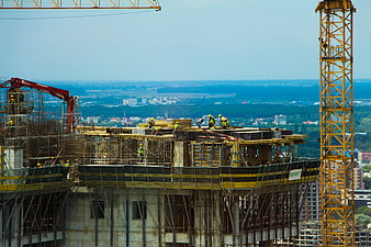 Construction workers on high-rise building with cranes and city view