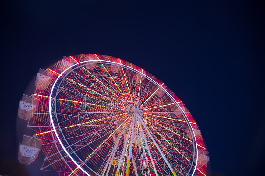 Illuminated Ferris Wheel at Night with Red and White Lights