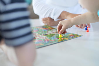 Child Playing Board Game with Family at Table