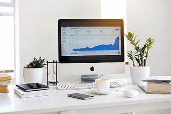 Minimalist white office desk with computer showing analytics chart
