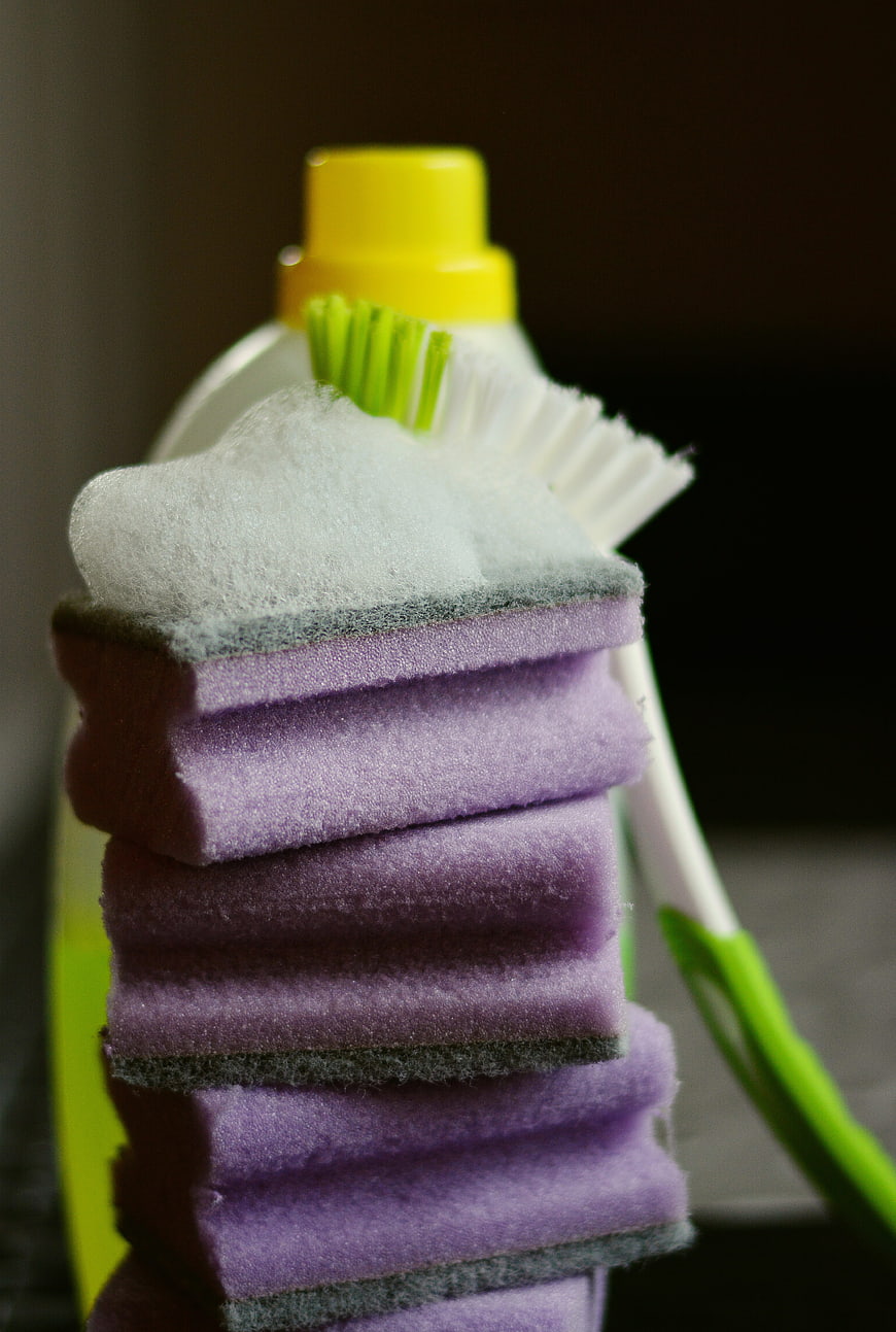 Stack of purple cleaning sponges with foam and brush