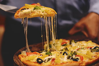 Close-up of a pizza slice being lifted with a long cheese pull