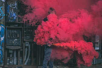 Man Holding Red Smoke Grenade in Urban Setting