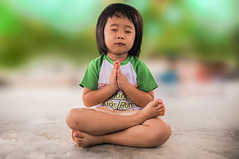 Cute little girl meditating with hands in prayer position