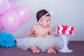 Baby girl smashing pink and white birthday cake