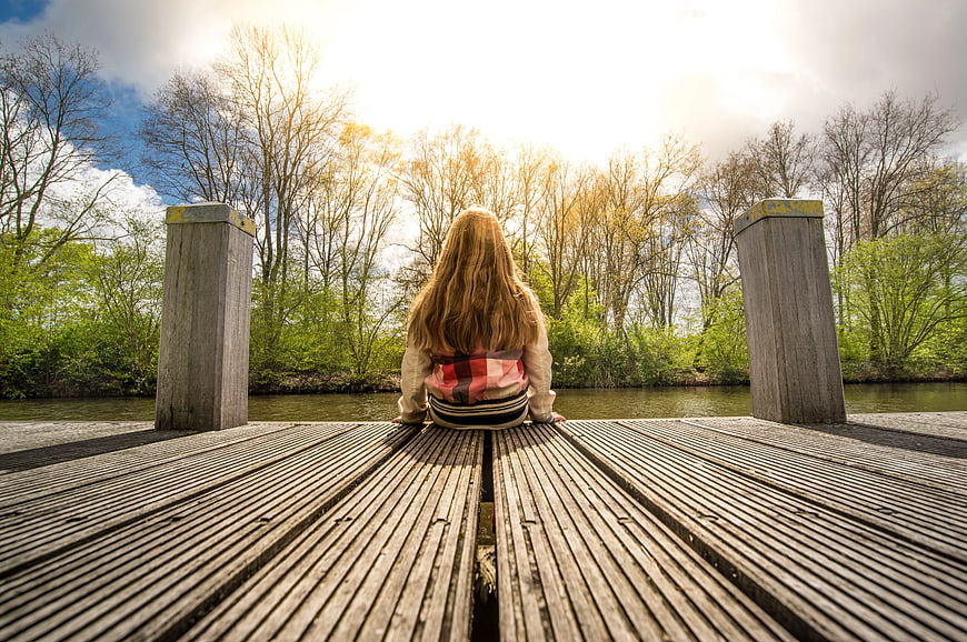 Woman Sitting on Wooden Bridge Looking at River