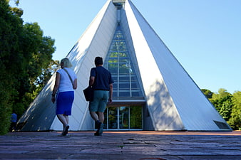 Couple walking toward modern pyramid building in botanical garden