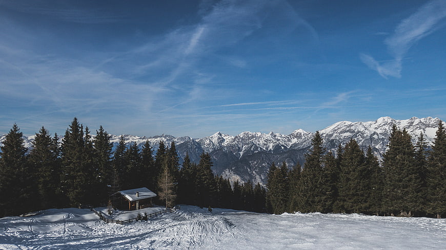 Snowy Mountain Cabin with Pine Forest and Blue Sky