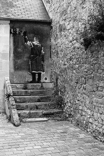Black and white street art mural of a figure on a stone wall