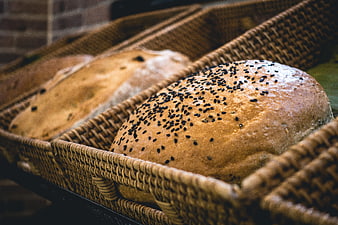 Fresh artisan bread loaves with black sesame seeds in wicker baskets