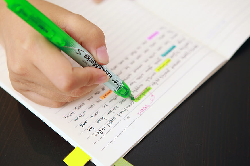 Hand Highlighting Text in Notebook with Green Marker