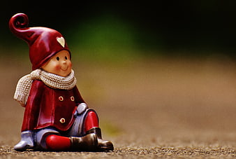 Cute Red Elf Figurine with Scarf Sitting Outdoors