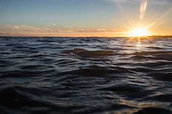 Sunset over ocean waves with lens flare and golden light