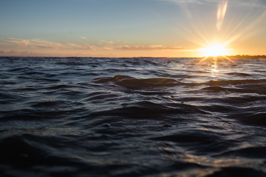 Sunset over ocean waves with lens flare and golden light