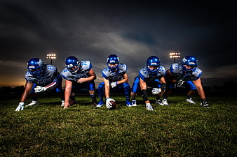 American football team lineup on field at dusk