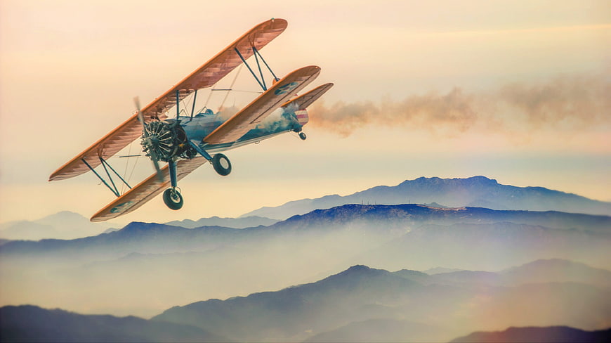 Vintage Biplane Flying Over Misty Mountain Landscape