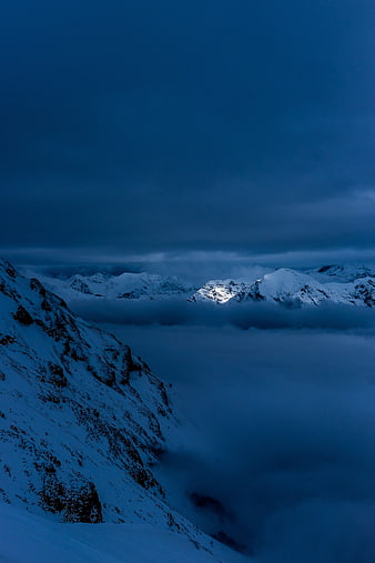 Snowy Mountain Peaks Rising Above Clouds at Blue Hour