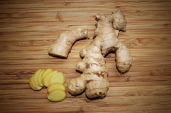 Fresh ginger root and slices on wooden cutting board