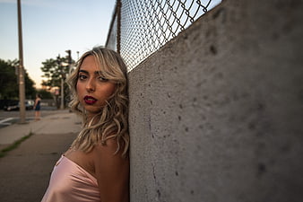 Blonde Woman in Pink Dress Leaning Against Concrete Wall