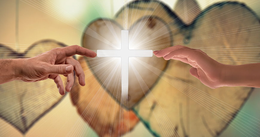 Two hands reaching toward glowing cross with heart background