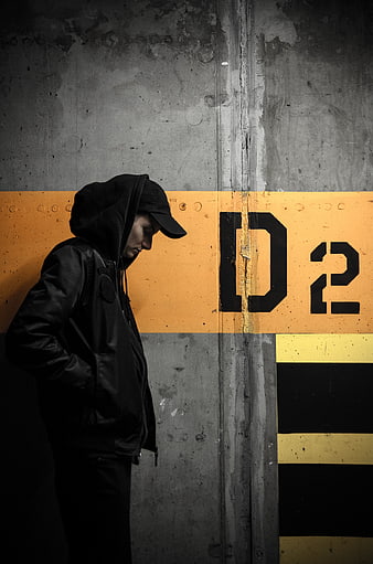 Man in Hoodie Standing Against Concrete Wall with Yellow Stripe