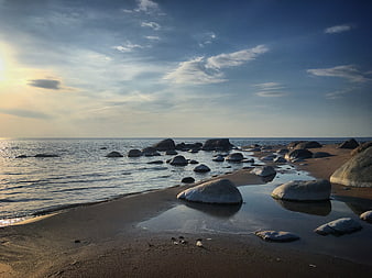 Serene Rocky Beach at Sunset with Calm Ocean Waves