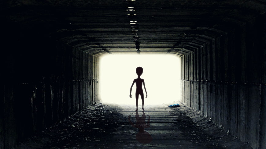 Silhouette of alien figure standing in dark tunnel