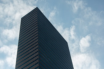 Low angle view of modern glass skyscraper against blue sky