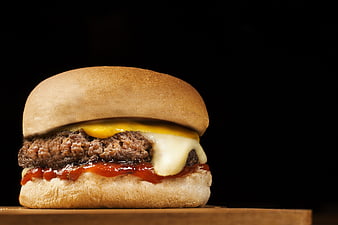 Delicious Cheeseburger on Wooden Board with Black Background