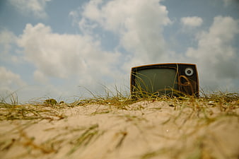 Vintage Television Set on Sandy Dune Under Blue Sky