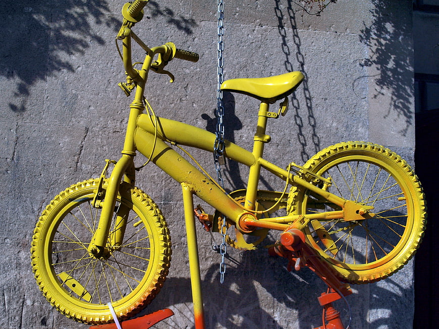 Yellow bicycle sculpture hanging on concrete wall
