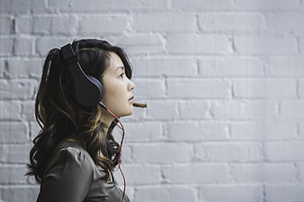 Woman with Headset Against White Brick Wall
