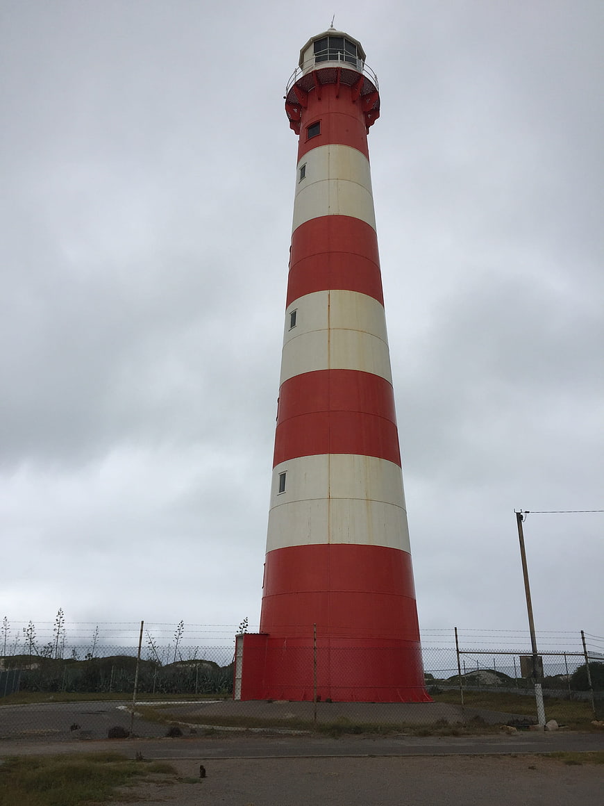 Red and white striped lighthouse against cloudy sky