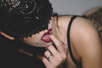 Sensual Woman in Black Lace Mask Licking Finger
