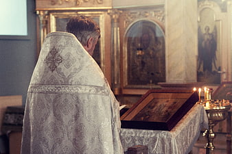 Priest in white vestments praying in Orthodox church