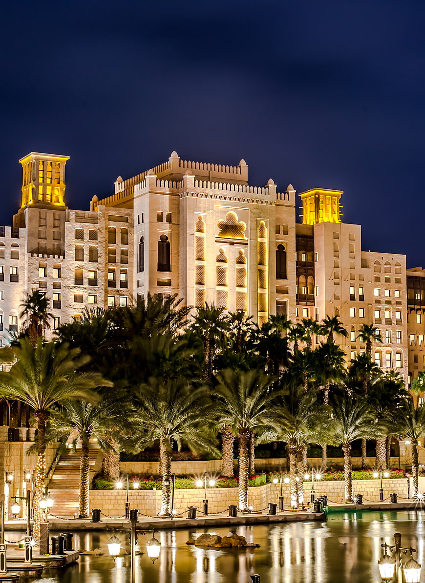 Luxury Arabian Hotel at Night with Palm Trees and Water Reflection