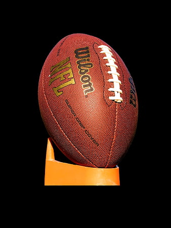 NFL Wilson American Football on Orange Stand Against Black Background